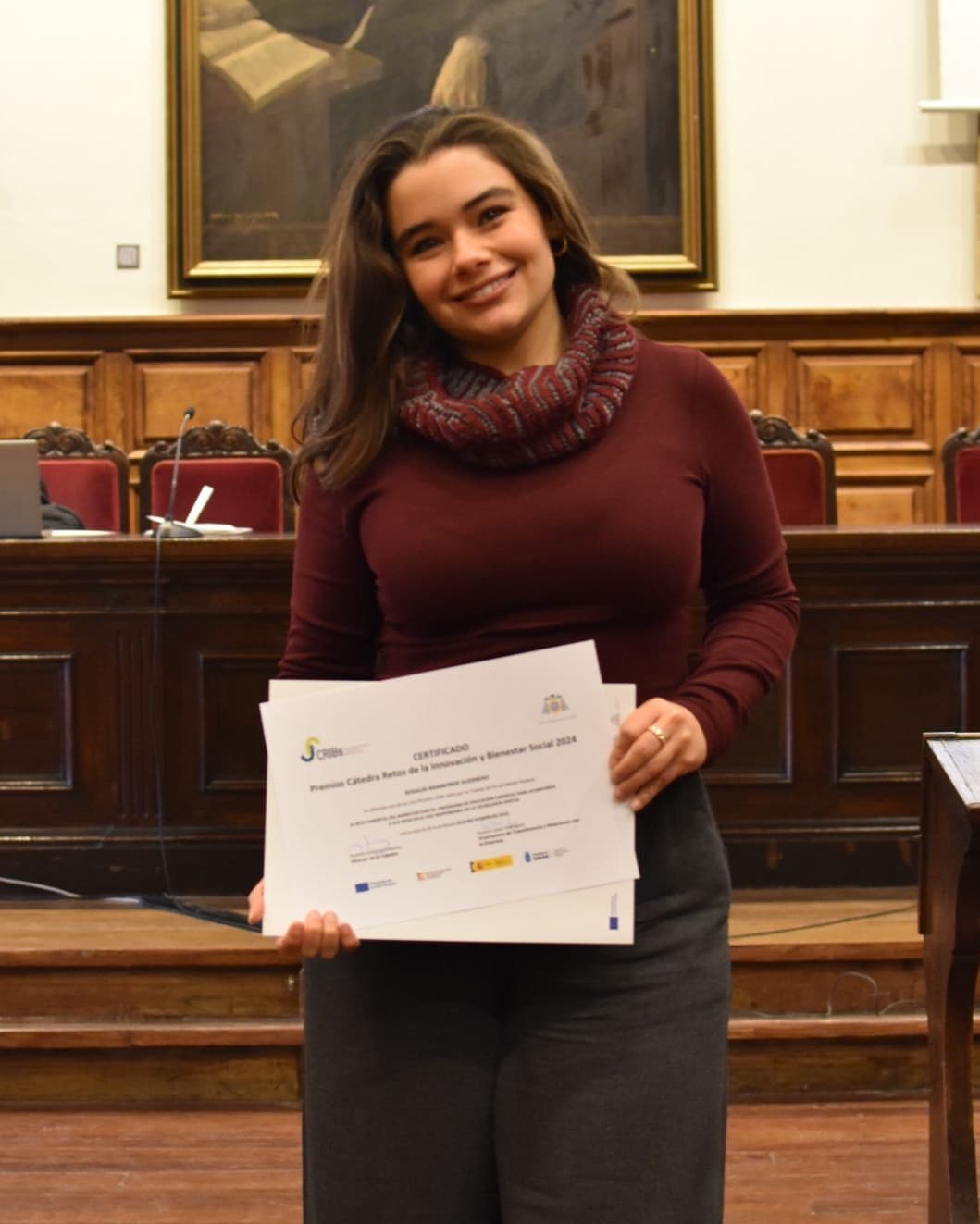 Investigadora sosteniendo un certificado de reconocimiento académico
