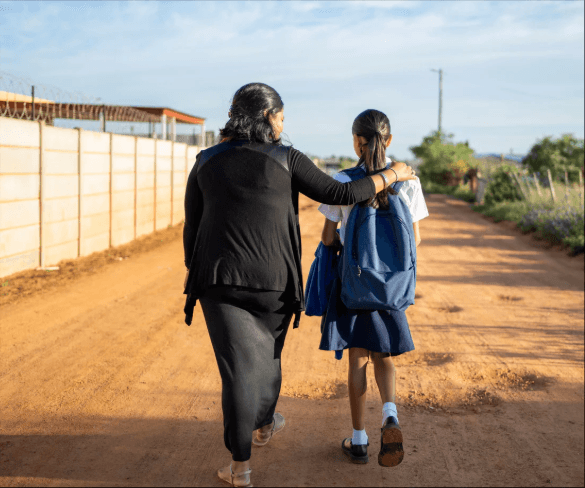 Persona adulta acompañando a una niña por un camino